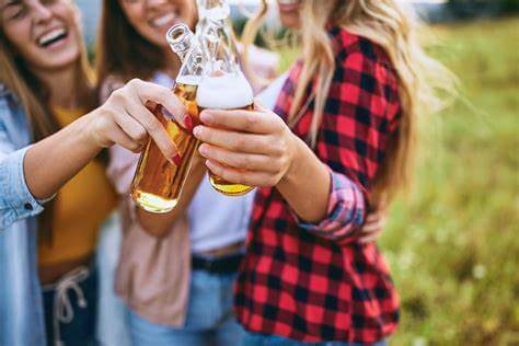eine Gruppe von Freunden im Freien, die gemeinsam Bierflaschen clinchen.