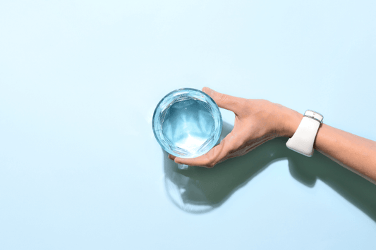 Hand holding a glass of water with blue background