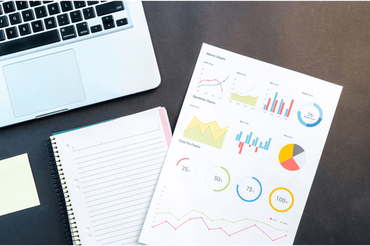 Clavier d'ordinateur visible en haut a gauche de l'image avec en bas un cahier ou figure des graphiques et données analytiques