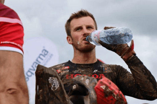 Man riding a motocross bike hydrating himself with a water bottle