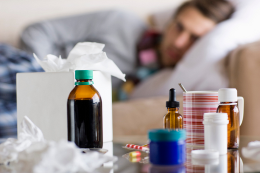 Mann im Bett, der sehr geschwächt und krank aussieht, mit Medikamenten auf dem Nachttisch