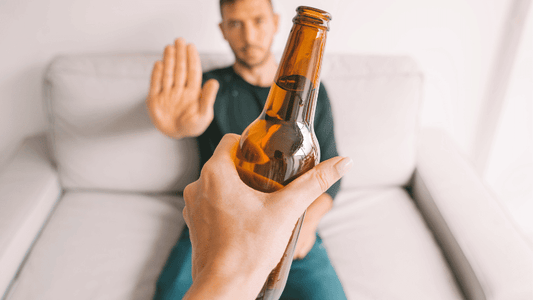 Homme tendant son bras refusant une bouteille d'alcool