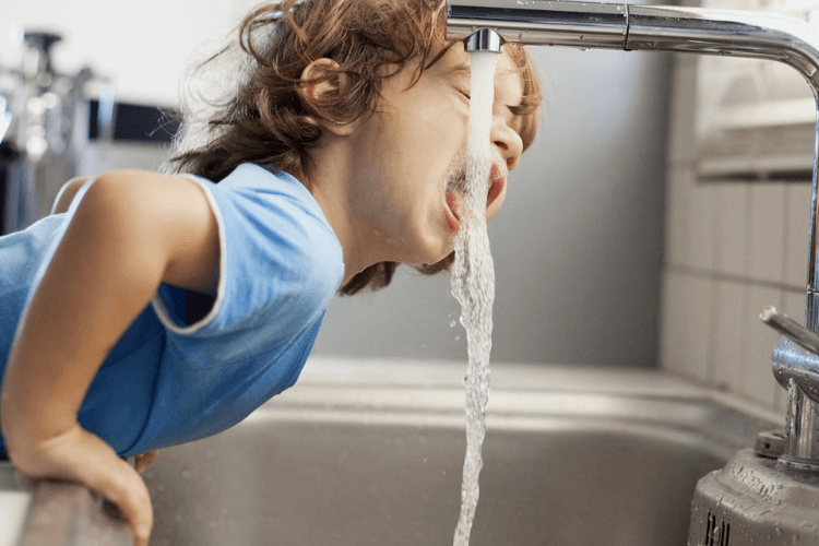 enfant qui boit de l'eau directement au robinet