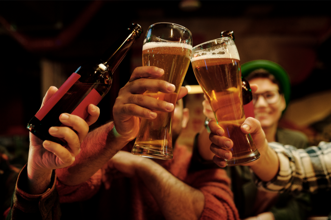 Jeunes personnes souriante dans un bar trinquant avec des verres de bière dans la main 