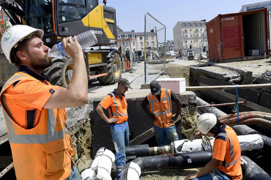 Travailleurs de la construction se reposant et s'hydratant sur un chantier par une journée chaude, soulignant l'importance de la sécurité et du bien-être des ouvriers.